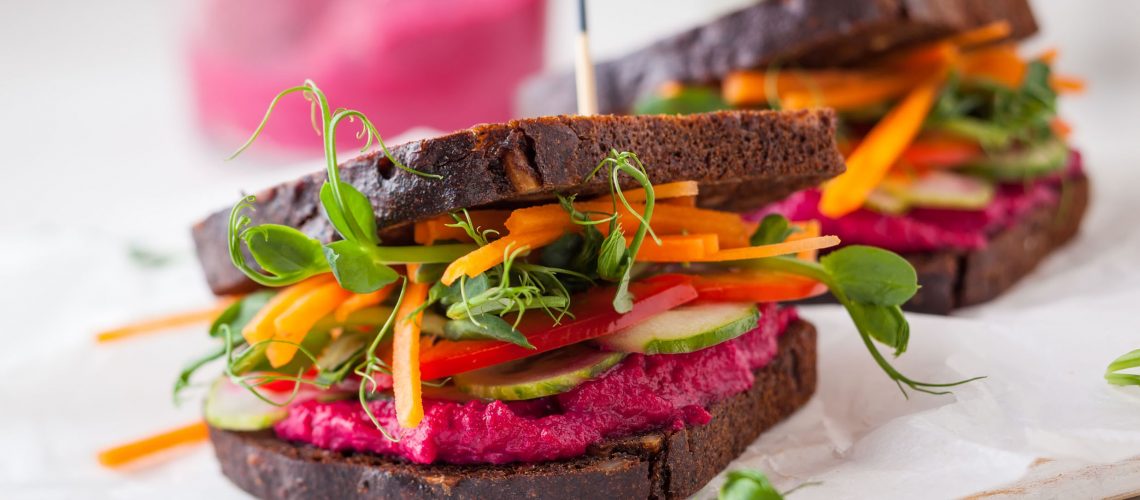 gluten free vegan sandwiches with beet hummus, raw vegetables and sprouts. soft focus
